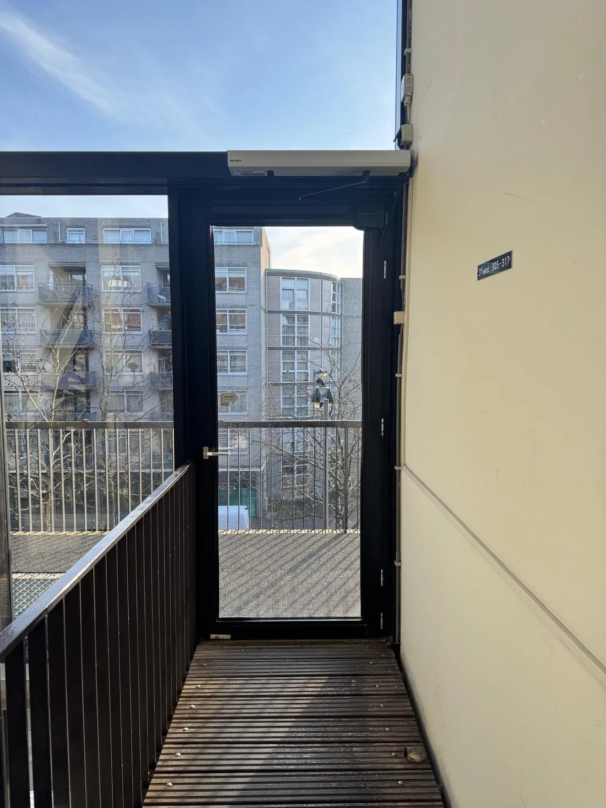 Galerijdeur met draaideurautomaat op het kozijn van een appartementencomplex